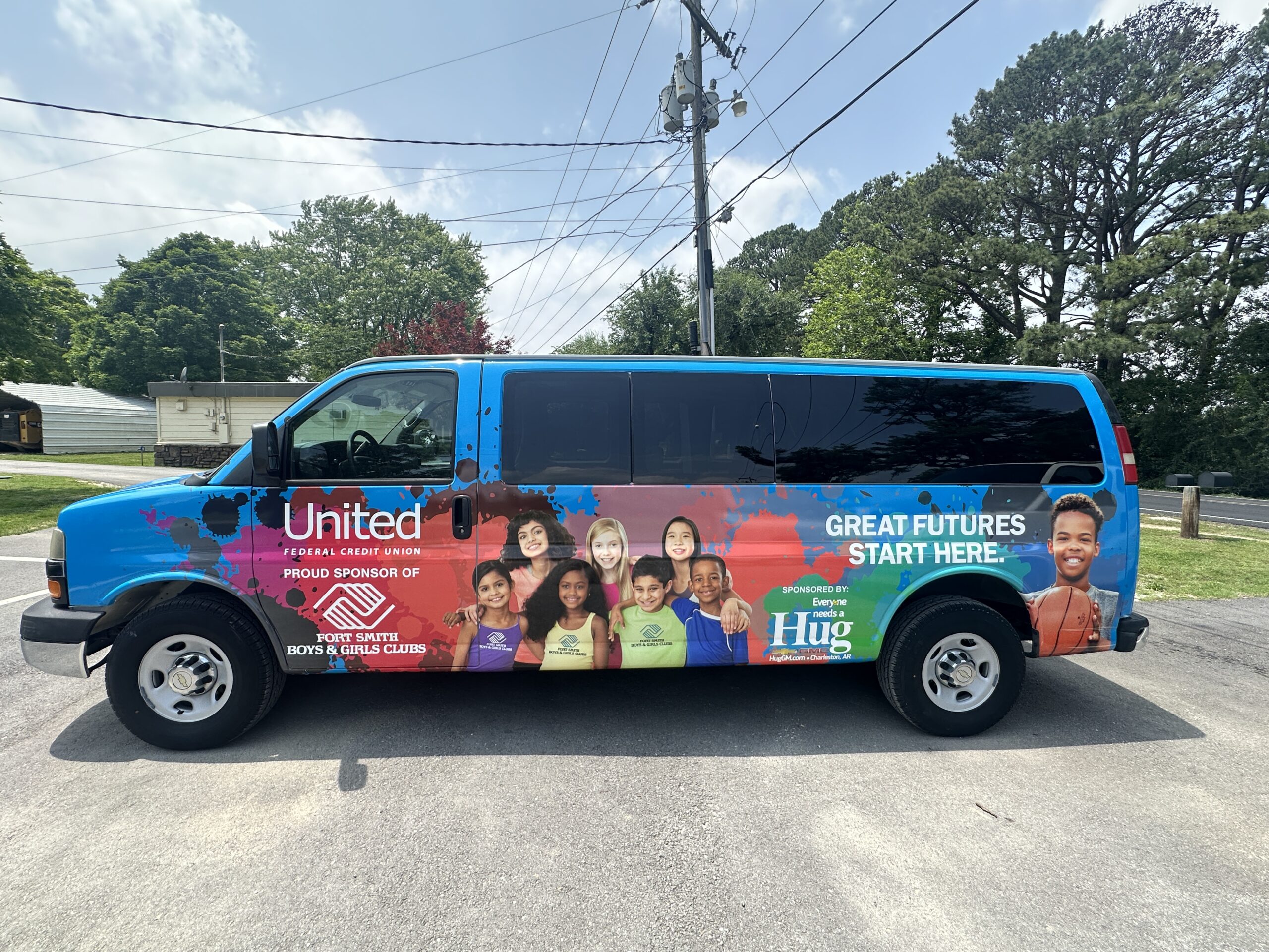 IMG_9927 A brightly colored van with eye-catching vinyl wraps features smiling children, Boys & Girls Club and United Federal Credit Union logos, and the slogan “Great Futures Start Here” against a blue background with trees and houses in the distance.