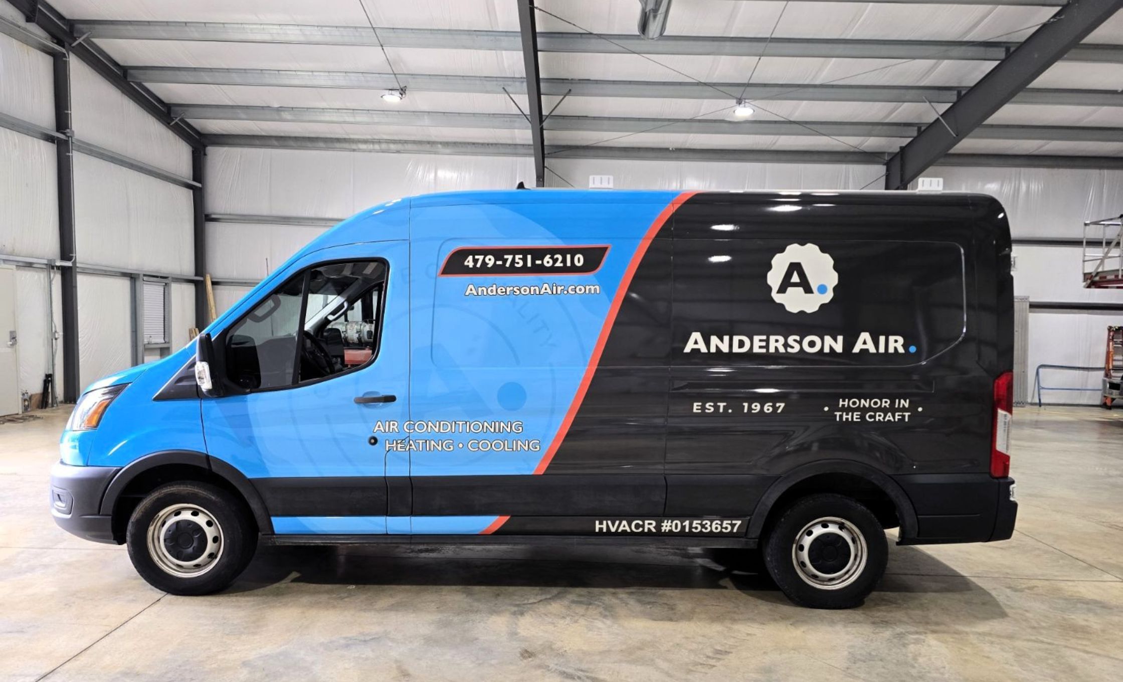 A blue and black Anderson Air van parked inside a large garage. The van advertises air conditioning, heating, and cooling services with contact info and the slogan Honor in the Craft on its side.